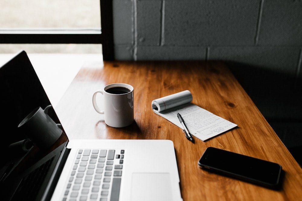 Website content packages - Laptop and notepad - Photo by Andrew Neel on Unsplash